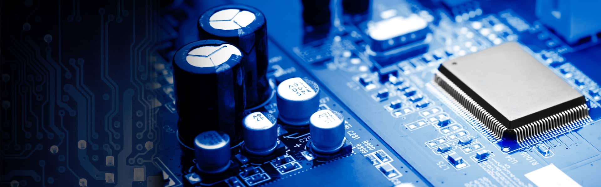 Close-up of electronic components, including capacitors and a microchip, on a blue printed circuit board.